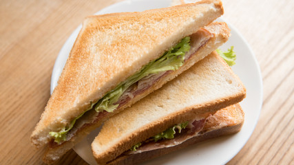 .cooked sandwich with salami and lettuce leaves. Fast snack for an office worker