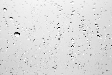 Rain drops on car window in black and white.