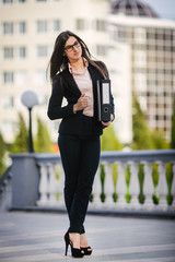brunette with folders stands in the square