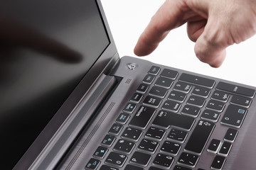 Silver laptop and moving man's hand catching start button, on white background