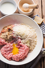 Meatballs ingredients in the bowl. Minced pork meat, seasoning, breadcrumbs, egg yolk, parmesan cheese. 