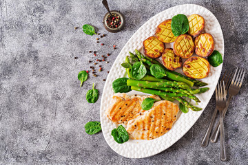 Chicken fillet cooked on a grill with a garnish of asparagus and baked potatoes. Dietary menu. Healthy food. Flat lay. Top view