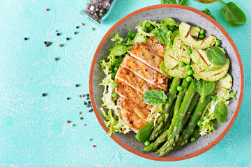 Chicken fillet cooked on a grill with a garnish of asparagus and grilled avokado. Dietary menu. Healthy food. Flat lay. Top view