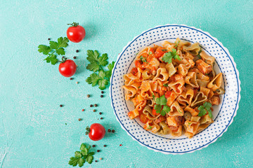 Pasta in the shape of hearts with chicken and tomatoes in tomato sauce. Top view