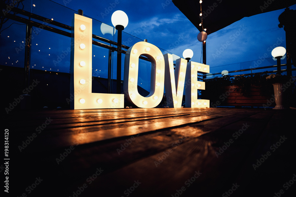 Wall mural Word love from big, letters with glowing light bulbs on a dark b - Wall murals