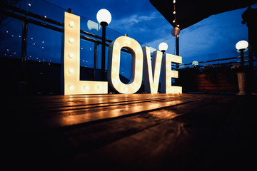 Word love from big, letters with glowing light bulbs on a dark b