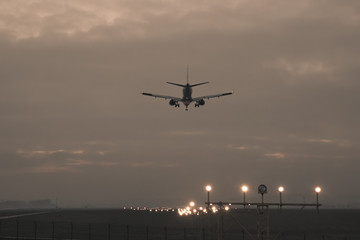 Fototapeta na wymiar A passenger plane is landing on the background of the twilight, photo in retro style