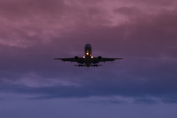 Fototapeta na wymiar A passenger plane takes off against the background of dusk and the dark blue and purple sky, view from below