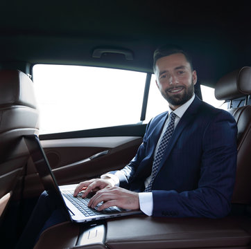 Businessman working on laptop keyboard sitting in car