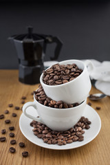 Coffee beans in the cup and coffee percolator on wooden table with black background