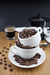 Espresso shot, coffee beans in the cup and coffee percolator on wooden table with black background