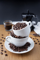 Espresso shot, coffee beans in the cup and coffee percolator on wooden table with black background