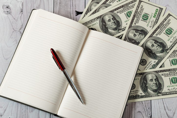Notepad, pen and money on a light wooden background