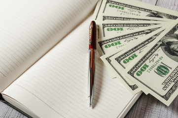 Notepad, pen and money on a light wooden background