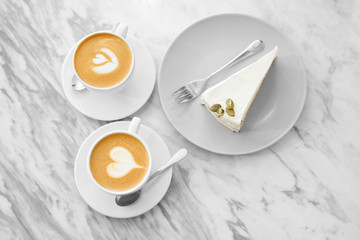 Two cups of coffee with cake art on white background