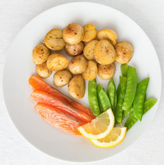 a plate with freshly salted salmon, fried young potatoes, and sweet pea pods