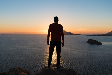 Silhouette of man is watching sunset over the sea