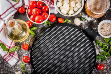 Homemade pasta pizza italian food ingredient on dark rusty table with flour, olive oil, basil, tomatoes and kitchen accessories top view