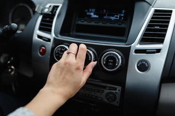 Woman's hand switches the air conditioning in the car. Driver turning on car air conditioning system