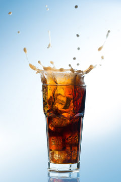 Ice splashing on a glass of a Cola drink