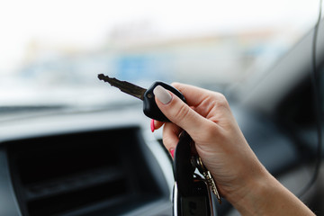 Car keys in the hand of a girl in the car interior. Woman holding car keys. Close up Hand