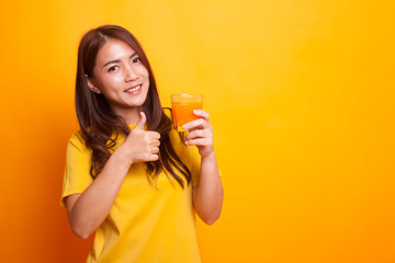 Young Asian woman thumbs up drink orange juice in yellow dress