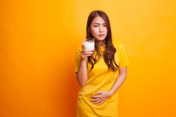 Asian woman drinking a glass of milk got stomachache in yellow dress