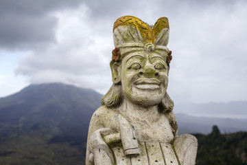 Traditional Balinese sculpture against the background of the volcano Batur. Island Bali, Indonesia