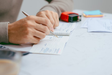 Man writing a payment check at the table with calculator and stamp