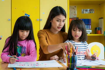 Asian teacher and preschool student in art class