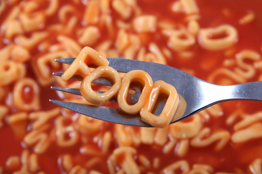 Spaghetti letter spelling the word food with the letters held up on a fork.