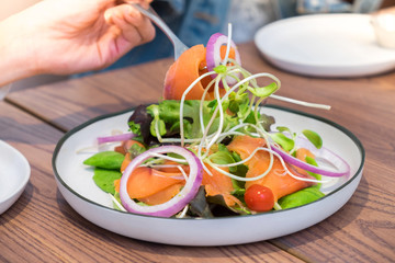 A Fork dipped Sashimi salad fresh sliced of salmon with fresh mixed vegetable served with spicy sauce
