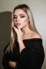 Fototapeta premium Pretty blonde woman with naked shoulders posing at the white wall