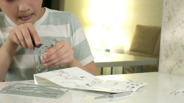 The boy creates a plastic model airplane, an exact copy, from the designer