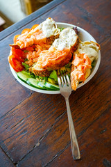 Salad with smoked salmon in slices of soft bread with a delicate cream. Restaurant with a wooden table. A girl in pink sits at a table and eats a salad. Top view with copy space