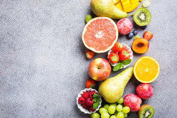 Fresh assorted fruits and berries on light gray background. Colorful clean and healthy eating. Detox food. Copy space. Top view.