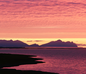 Fototapeta na wymiar Incredibly beautiful dawn (sunset) on the shore of the Atlantic Ocean. Silhouettes of mountains and red clouds. Iceland. 