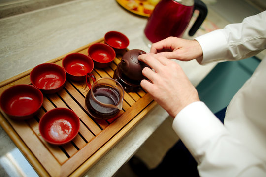 tea master pours tea on glasses from clay pot