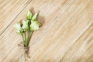 Small delicate flowers of eustoma on a wooden surface. Small bouquet on aged wood table.