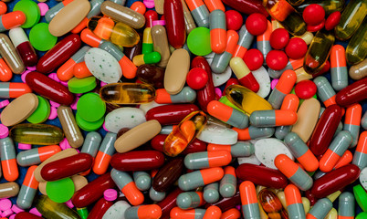 Pile of colorful tablets and capsule pills. Full frame of medicine, vitamins and supplements. Top view many of pills background. Drug, vitamin, supplement and herbal medicine interaction concept.