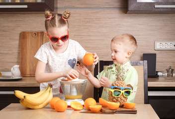 Healthy food: a girl and a boy make fresh orange juice.