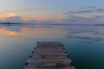 Naklejka premium Pier on the mountain lake during sunset