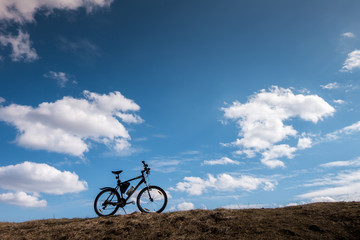 Bike silhouette in blue sky with clouds. symbol of independence and freedom