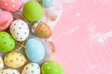 Happy easter! Colorful of Easter eggs in nest with paper star, flower and Feather on pastel color bright pink and white wooden background.