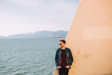 Fototapeta premium Young man thinks about life behind him is seen the sea and beautiful new spring