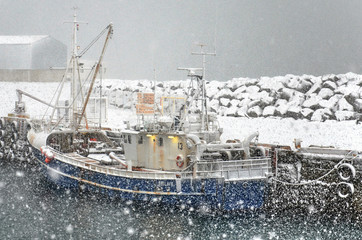 Keflavik, Iceland, February 29, 2012: Fishing boat seeking shelter in the harbour during a snowstorm