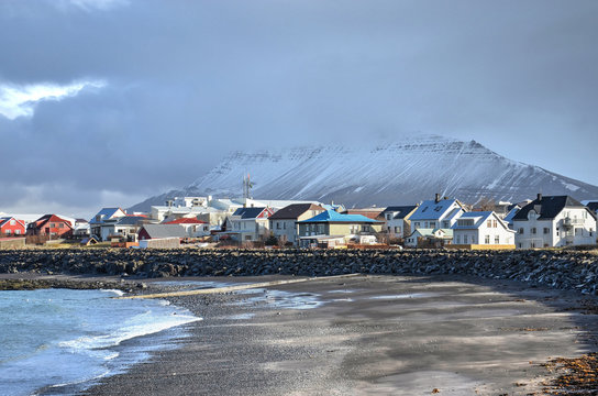 Akranes, Iceland, February 28, 2012: Colorful houses next to the beach with mountains partially obscured by clouds in the background