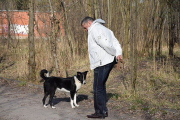 кавказский старик выгуливает молодого пса весенним днем