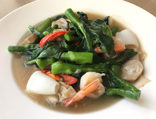 Wide rice noodle in creamy gravy sauce with shrimp and squid, traditional Chinese and Thai style food