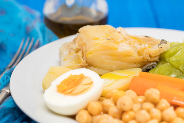 boiled cod fish with potato, carrot, cabbage , chick-pea and egg on white plate